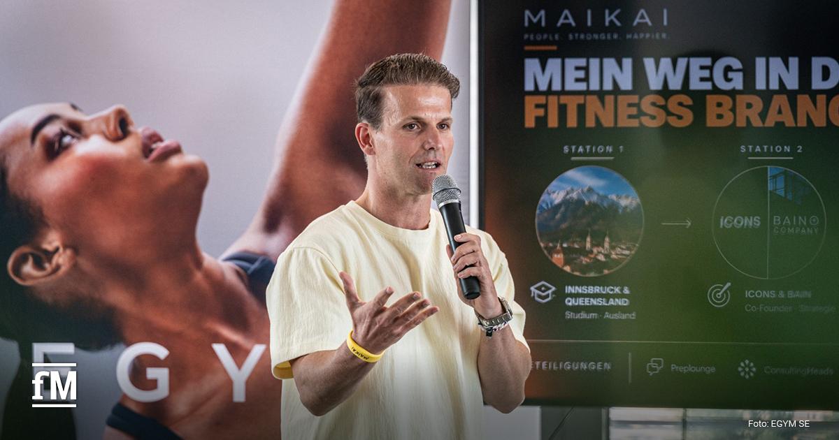 Referent spricht mit Mikrofon vor sitzenden Teilnehmern in einem Veranstaltungsraum