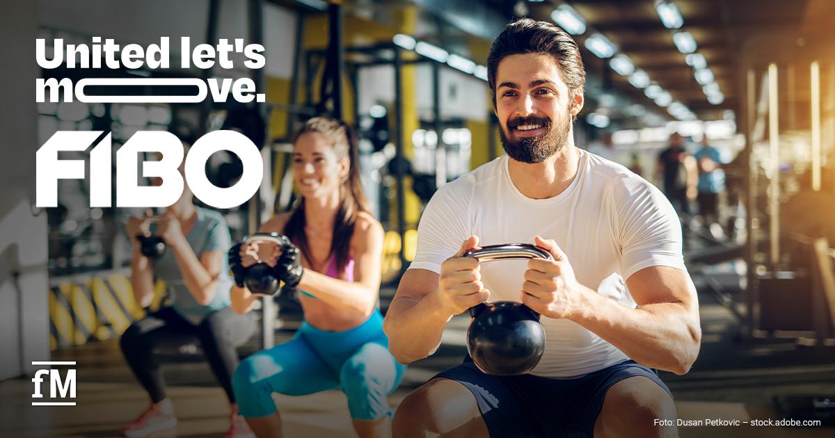 FIBO „United let's move.“ 2026 Drei Personen trainieren mit Kettlebells in einem Fitnessstudio. Im Vordergrund hält ein lächelnder Mann eine schwarze Kettlebell. Links stehen groß die Schriftzüge „United let’s move.“ und „FIBO“, darunter das fM-Logo.