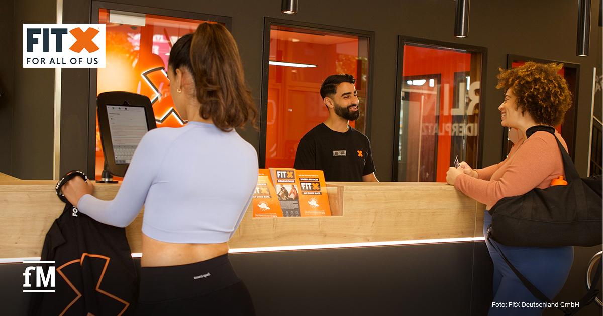 FitX Eröffnung Aachen-Mitte Zwei Frauen und ein Mitarbeiter stehen am Empfang eines FitX-Studios