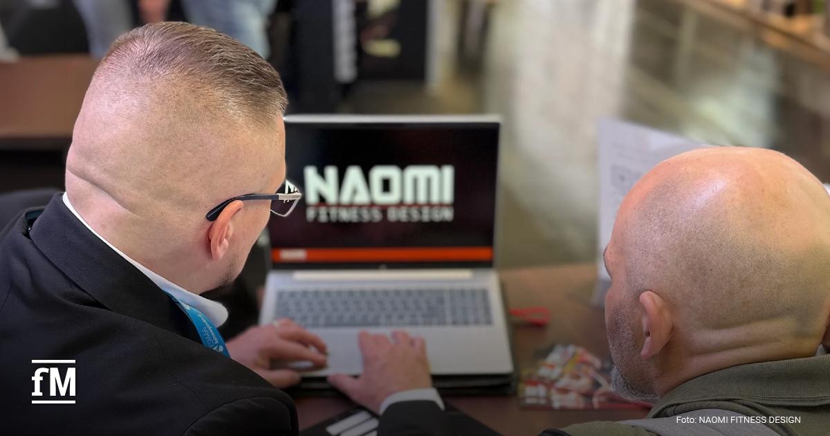 NAOMI FITNESS DESIGN Expansion Zwei Personen betrachten an einem Laptop eine Präsentation von NAOMI FITNESS DESIGN.
