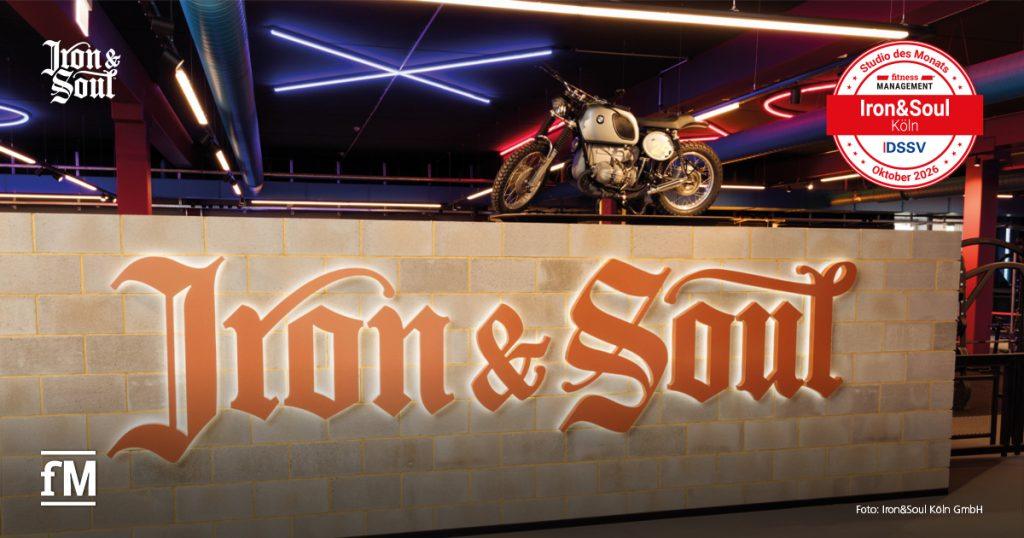 Trainingsbereich von Iron&Soul Köln mit beleuchtetem Iron&Soul-Schriftzug und Motorrad.