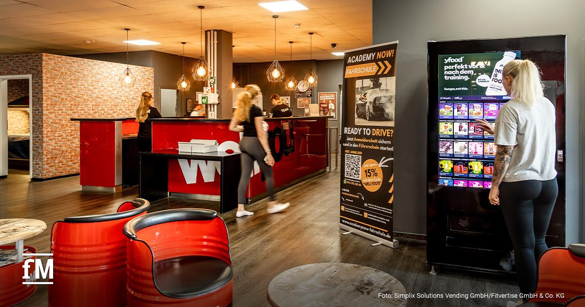 yfood an Smart-Vending-Automaten im Fitnessstudio Person vor einem Smart-Vending-Automaten mit yfood-Produkten in einem Fitnessstudio.