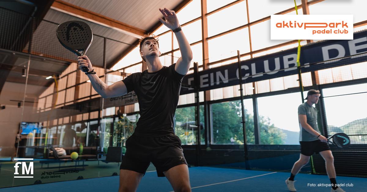 aktivpark padel club Kall Zwei Männer spielen Padel auf einem Indoor-Court. Im Vordergrund bereitet sich ein Spieler mit Schläger auf den Ball vor.