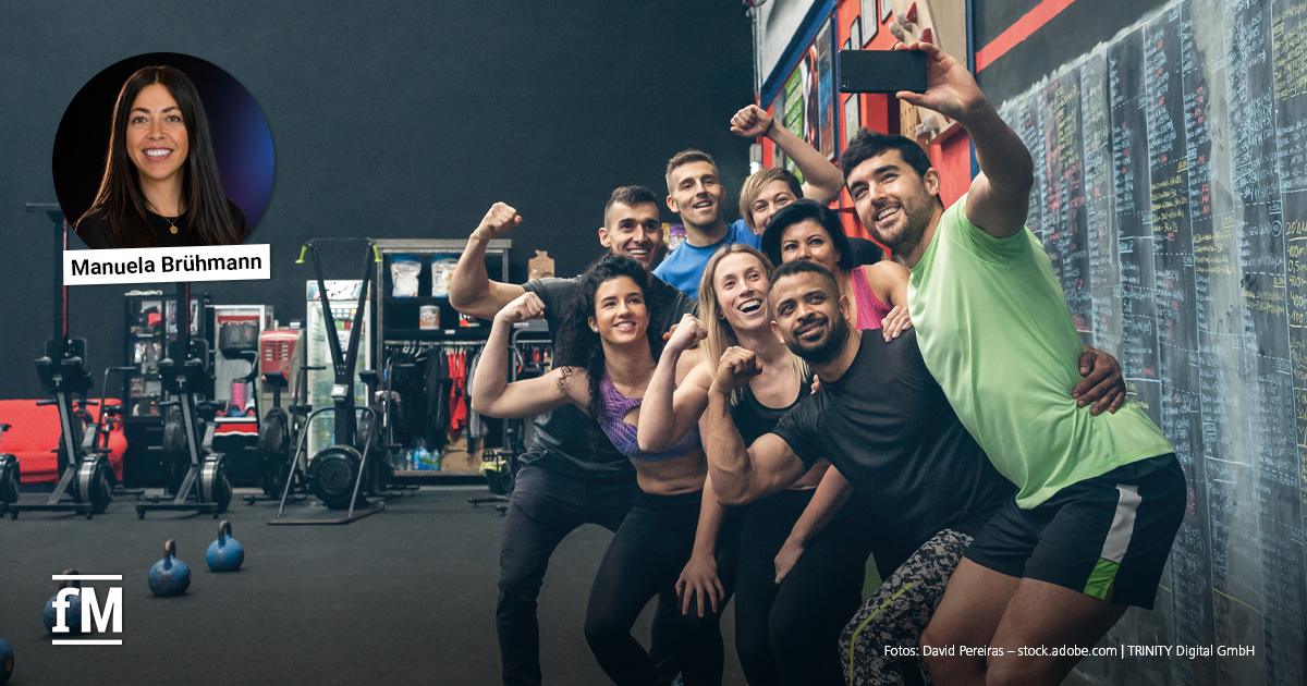 Science Lab Manuela Bruehmann Acht Personen in Sportkleidung posieren gemeinsam vor einer Tafel in einem Fitnessstudio.