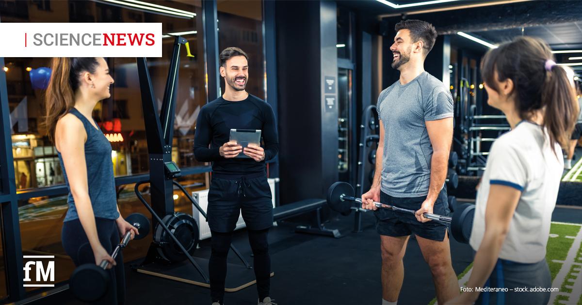 Science News: Selbstwirksamkeit, Motivation und Trainingsbeteiligung Vier Personen unterhalten sich im Fitnessstudio, zwei halten Hanteln, eine Person ein Tablet
