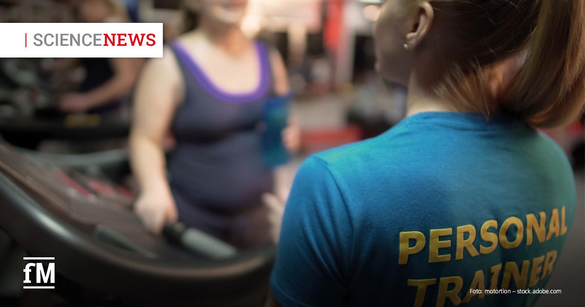 Rechts im Vordergrund steht eine Person mit Pferdeschwanz in blauem Shirt, auf dessen Rücken in gelben Großbuchstaben „PERSONAL TRAINER“ steht. Links davor steht unscharf eine Frau in dunklem Sporttop mit violetten Trägern an einem Cardiogerät. Oben links ist ein weißes Feld mit der Aufschrift „SCIENCE NEWS“ zu sehen.