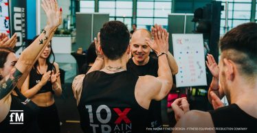 Im Fitnessstudio klatschen sich Menschen in Sportkleidung gegenseitig ab.