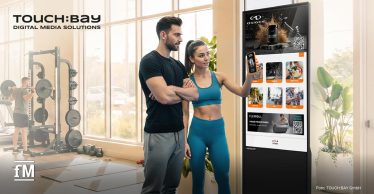 Zwei Fitnessstudiomitglieder bedienen einen digitalen TOUCH:BAY-Touchscreen im Trainingsbereich.