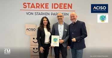 Drei Personen stehen vor einer Messewand mit den Schriftzügen „STARKE IDEEN“ und „VON STARKEN PARTNERN“. Links eine Frau in schwarzem Blazer und weißem Oberteil, mittig ein Mann mit Brille und grauem Sakko, rechts ein Mann in dunklem Sakko und Jeans.
