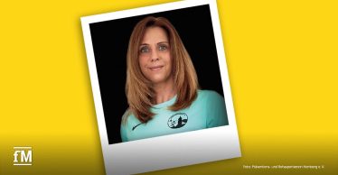 Porträtfoto als Sofortbild von Martina Scheller vor schwarzem Hintergrund, im türkisfarbenen Sportshirt mit Logo. Hinter dem Foto eine gelbe Fläche, rechts kleine Bildquelle und links unten das fM Logo.