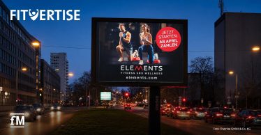 Großplakat an einer mehrspurigen Straße bei Nacht.