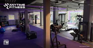 Fitnessstudio-Innenraum mit Kraftgeräten, Functional-Training-Bereich, violettem Boden und Anytime Fitness Logo.