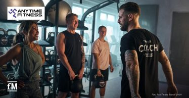 Coach spricht mit drei Personen im Trainingsbereich eines Anytime-Fitness-Clubs