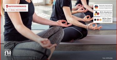 Mehrere Personen sitzen im Schneidersitz auf Yogamatten und halten ihre Hände in einer Meditationshaltung. Symbolbild für Entspannung, Regeneration und Achtsamkeitstraining beim Aufstiegskongress 2025 in Mannheim.