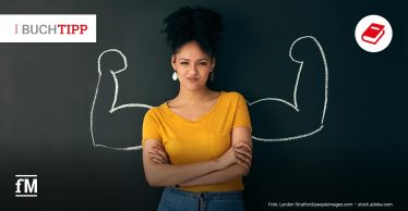 Buchtipp 'Women at work' von Silke Rusch: Eine junge Frau steht vor einer schwarzen Tafel, auf der links und rechts von ihr zwei muskulöse Oberarme gezeichnet sind. Sie trägt ein gelbes T-Shirt, blickt selbstbewusst in die Kamera.