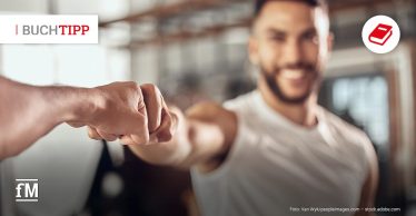 Sportlicher junger Mann mit Bart vor Spiegel im Fitnessstudio