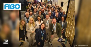 Große Gruppe von Teilnehmenden eines CEO-Frühstücks auf der FIBO steht dicht zusammen und blickt lächelnd in die Kamera.