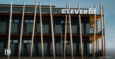 Außenansicht des clever fit Gebäudes mit Holzstützen und Logo