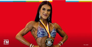 Lea Oberfichtner mit Wettkampfmedaille in Bodybuilding-Pose.
