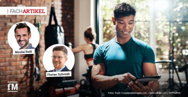 Ein junger Mann im Sportoutfit steht in einem modernen Fitnessstudio und bedient ein Tablet mit einem Lächeln im Gesicht. Im Hintergrund trainiert eine Frau an einem Boxsack vor einer Wand aus roten Backsteinen. Oben links im Bild ist der Hinweis 'FACHARTIKEL' zu sehen. Darunter befinden sich zwei Porträtfotos: links Nicolai Rolli, rechts Florian Schmidt.