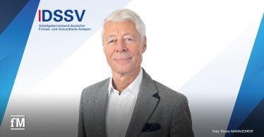 Porträt eines weißhaarigen Mannes (Thomas Wessinghage) in grauem Sakko vor dem Logo des DSSV mit Schriftzug 'Arbeitgeberverband deutscher Fitness- und Gesundheits-Anlagen'.