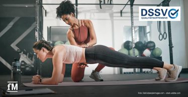 Eine Trainerin unterstützt eine Kundin bei einer Fitnessübung auf der Matte in einem modernen Trainingsraum. In der oberen rechten Ecke ist in blauer Schrift auf weißem Grund das Logo 'DSSV Qualitätsoffensive' zu sehen.
