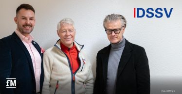 Drei Männer (von links Janosch Marx, Thomas Wessinghage, Ralf Capelan) stehen Schulter an Schulter vor einer weißen Wand, links und rechts in dunkler Kleidung, mittig in heller Jacke, oben rechts das DSSV-Logo.