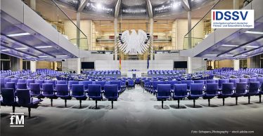 Großer Plenarsaal mit blauen Sitzreihen, Rednerpult und Bundesadler unter einer gläsernen Kuppel und DSSV-Logo rechts oben.
