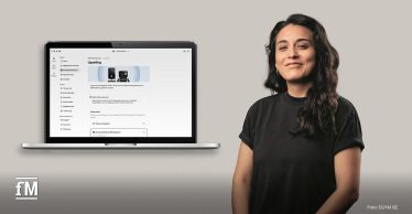Laptop mit geöffneter EGYM Business Suite neben einer Person vor neutralem Hintergrund