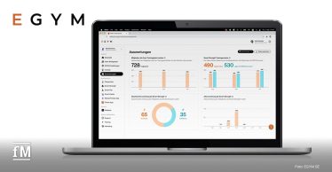 Laptop mit geöffnetem EGYM Business Suite Dashboard, das Diagramme und Analysen anzeigt, EGYM Logo links oben in der Ecke und rechts unten das weiße fM Signet.