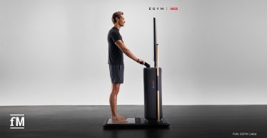 Ein Mann steht barfuß auf der Messplattform des EGYM Fitness Hub seca edition und hält die Handgriffe für eine integrierte seca Körperanalyse.