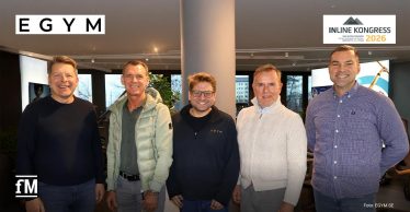Fünf Männer (Alexander Benker, Thorsten Kielmann, Philipp Roesch-Schlanderer, Paul Underberg und Jan Scherzer) stehen lächelnd nebeneinander in einem modernen Fitnessstudio.