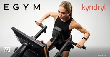 Sportlerin trainiert an einem schwarzen Fitnessgerät mit Display und beweglichen Griffen.