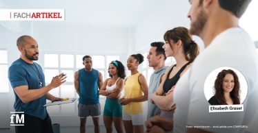 Im Vordergrund links steht ein Trainer mit Klemmbrett und spricht zu einer Gruppe von sechs Personen in Sportkleidung, die halbkreisförmig im hellen Kursraum stehen; große Fenster im Hintergrund, rechts ein eingeblendetes Porträtfoto von Elisabeth Graser