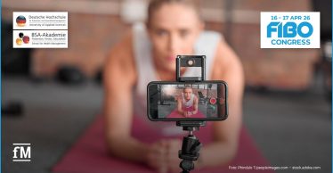 Frau trainiert vor Smartphone-Kamera und erstellt Fitnesscontent für Social Media im Studiokontext