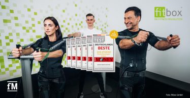 Drei Personen beim EMS-Training mit Trainingsgerät im Studio.