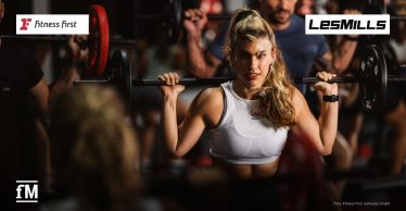 rau trainiert mit einer Langhantel in einem Groupfitness-Kurs; Logos von Fitness First und Les Mills