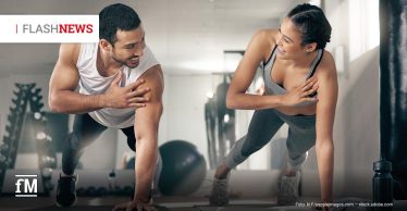 Zwei Personen machen im Fitnessstudio seitliche Planks und lächeln sich an; oben links steht „FLASHNEWS“, unten links das fM-Logo.