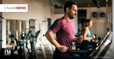 Mann in bordeauxfarbenem Sportshirt joggt auf einem Laufband im Fitnessstudio, im Hintergrund läuft eine weitere Person auf einem zweiten Laufband. Oben links steht „FLASHNEWS“.