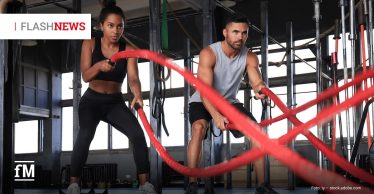 Zwei Personen trainieren in einem Fitnessstudio mit roten Battle Ropes. Sie stehen in leichter Kniebeuge und schwingen die Seile kraftvoll vor sich. Oben links steht „FLASH NEWS“, unten links das fM-Logo.