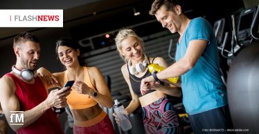 Vier sportlich gekleidete Menschen stehen gut gelaunt in einem Fitnessstudio zusammen