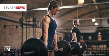 Zwei trainierende Personen heben Langhanteln in einem Fitnessstudio; im Vordergrund eine Frau in Sportkleidung, im Hintergrund ein Mann – beide konzentriert beim Kreuzheben.