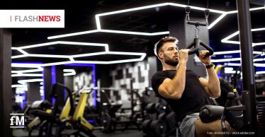 Mann trainiert an einem Kabelzug in einem Fitnessstudio mit moderner Beleuchtung.