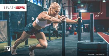 Fitness Flash News #31/2025 HYROX Eine Frau schiebt in einem Fitnessstudio ein mit Gewichten beladenes Trainingsschlittengerät und trainiert für ein HYROX-Event.
