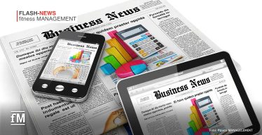 Mehrere Zeitungen mit der Überschrift 'Business News' liegen auf einem Tisch, darauf befinden sich ein Smartphone und ein Tablet, die ebenfalls digitale Versionen derselben Zeitung anzeigen. Die Inhalte zeigen farbige Diagramme, eine Taschenrechner-Grafik und Wirtschaftsartikel. Im oberen linken Bereich des Bildes steht 'FLASH-NEWS fitness MANAGEMENT' in roter und schwarzer Schrift. Unten links ist das 'fM'-Logo zu sehen. Die Bildquelle ist 'fitness MANAGEMENT'.