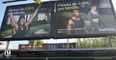 TrainToGo-Werbekampagne auf einer großflächigen Außenwerbeanlage mit zwei Fitnessmotiven und dem Slogan „Fitness ab 0,09 € pro Minute“.