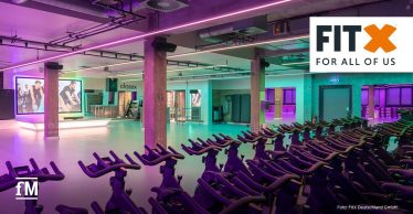 Großer Kursraum mit Indoor Bikes, farbiger LED-Beleuchtung und Trainingsfläche.