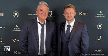 Frank Böhme (links) steht in dunkelblauem Anzug und graukarierter Krawatte vor einer Sponsorenwand des Deutschen Gesundheitsballs, rechts neben ihm steht ein weiterer Mann, ebenfalls im dunkelblauem Anzug und gleichfarbiger Krawatte. Beide Männer tragen weiße Hemden.