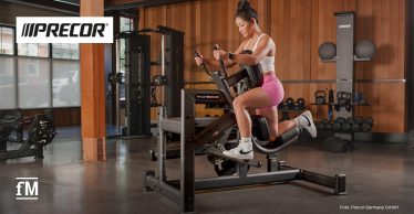 Person trainiert an einem Precor-Glutebuilder-Gerät in einem modernen Fitnessstudio. Links oben das Precor Logo, links unten das fM Signet.