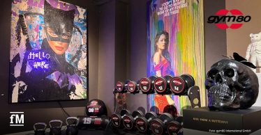 Hanteln, Kettlebells und Pop-Art-Bilder in einer Ausstellung mit Skulptur.